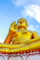 Big golden buddha statue on blue sky background.