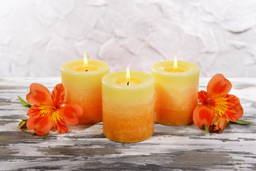 Fototapeta na wymiar Beautiful candles with flowers on table on grey background
