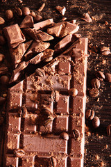 Chopped bar of milk chocolate on wooden background