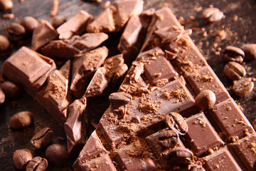 Chopped bar of milk chocolate on wooden background