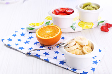 Various sliced fruits in bowls on table close-up