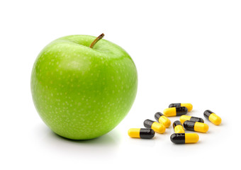 Green apple and pills capsules isolated on white background