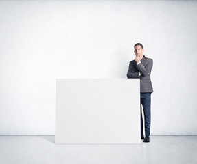 Thoughtful businessman and blank poster