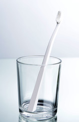 Toothbrush in glass on light grey background