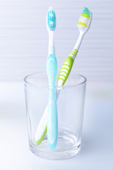 Toothbrushes in glass on table on light background