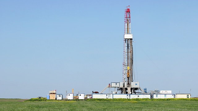 oil drilling rig on green wheat field