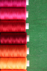 Multicolor sewing threads on wooden background