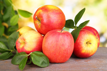 Ripe sweet apples with leaves on nature background
