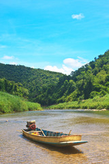 Plakat river in evergreen forest with boat