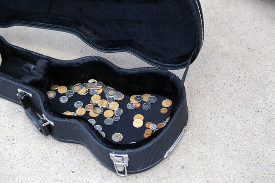 Coins in a guitar case in a street