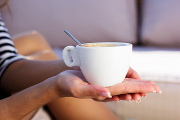 Young woman drinking coffee in a cafe outdoors