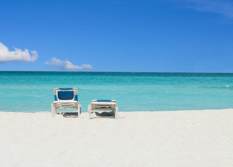 Romantic view of two sunbeds on gold sand beach