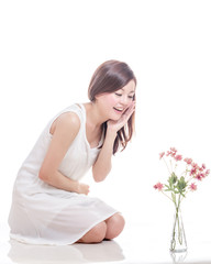 Asian woman kneeling and looking at flowers