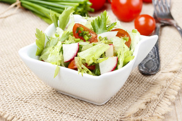 Bowl of fresh salad on wooden table