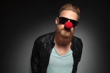 young bearded man wears a red nose