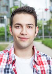 Student im kariertem Hemd lächelt in die Kamera