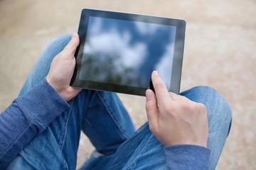 man sitting in the park and holding tablet