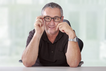 Gray-haired man with glasses sitting at desk