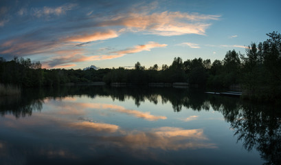 Fototapeta na wymiar Summer vibrant sunset reflected in calm lake waters