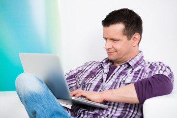 attraktiver mann sitzt interessiert am laptop