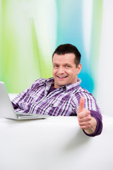 lachender mann am laptop zeigt daumen hoch