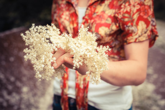 Young woman holding a bunch of elderflowers