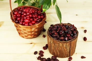 Fresh and dry cranberry in baskets on wooden table