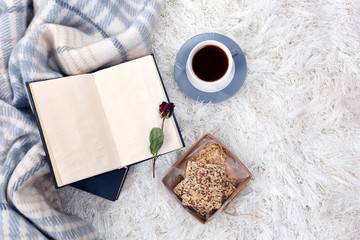 Composition with warm plaid, book, cup of hot drink