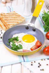 Scrambled eggs and bacon on frying pan on table close-up