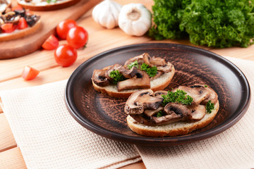 Delicious bruschetta with mushrooms on plate on table close-up