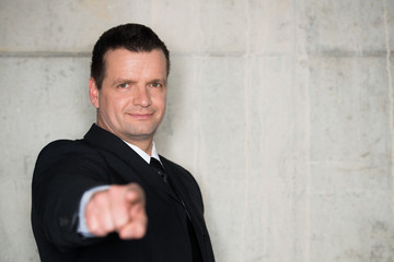 manager zeigt entschlossen mit dem finger richtung kamera