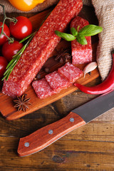 Tasty salami sausage and spices on wooden background