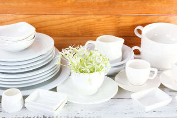 Different tableware on shelf, on wooden background