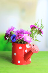 Bright wildflowers in decorative watering can,
