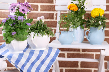 Fototapeta na wymiar Flowers in decorative pots on table, on bricks background