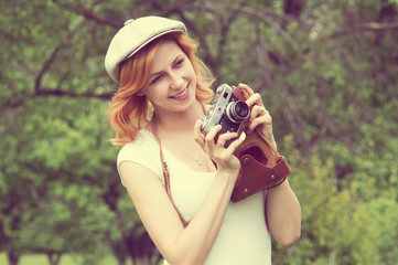 smiling girl in a cap with a camera in the garden