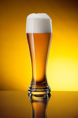 Glass of beer on yellow background
