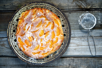 Cake with peaches, sprinkled with powdered sugar