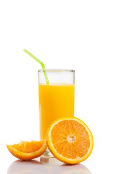 full glass of orange juice with straw near half orange