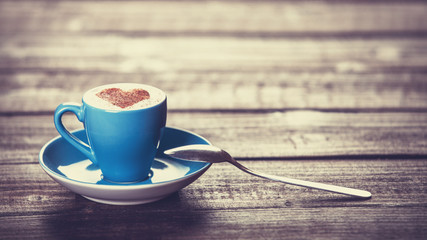 Cup of coffee with shape heart on a wooden table.