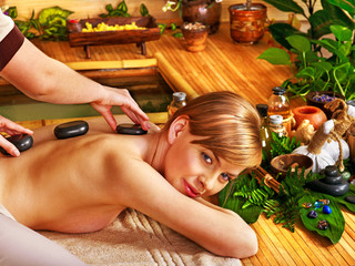 Woman getting stone therapy massage .