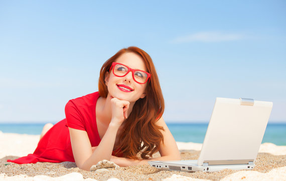 Redhead girl in the glasses with notebook on the beach