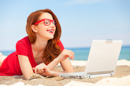 Redhead girl in the glasses with notebook on the beach