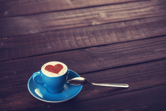 Cup of coffee with shape heart on a wooden table.