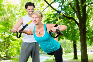 Fitness - Leute beim Suspension training im Park