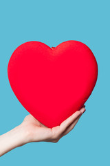 Hand holding shape heart on blue background.