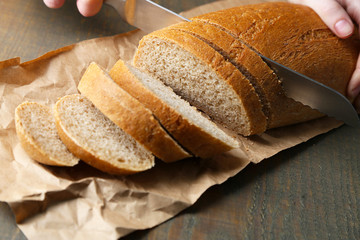 Female hands cutting bread on wooden board, close-up