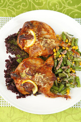 Roasted quails with vegetables on plate, on wooden background