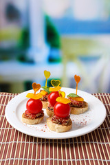 Tasty canapes with salami,tomato, pepper  and basil leaves,