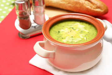 Tasty soup in saucepan on tablecloth, close up